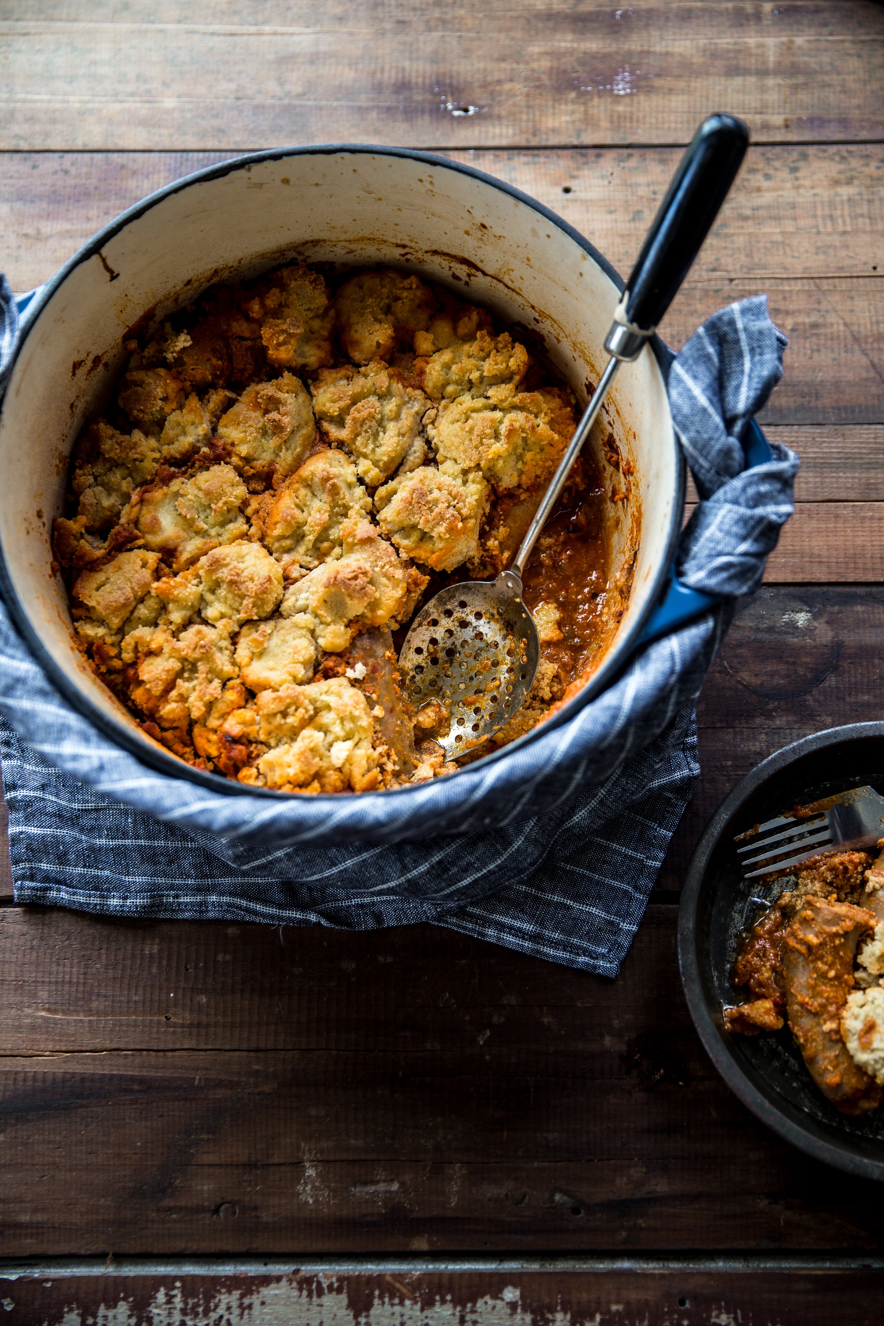 Baked dish with a spoon in a pot on a wooden surface